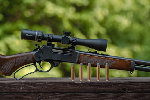a rifle and some bullet shells on a wooden table