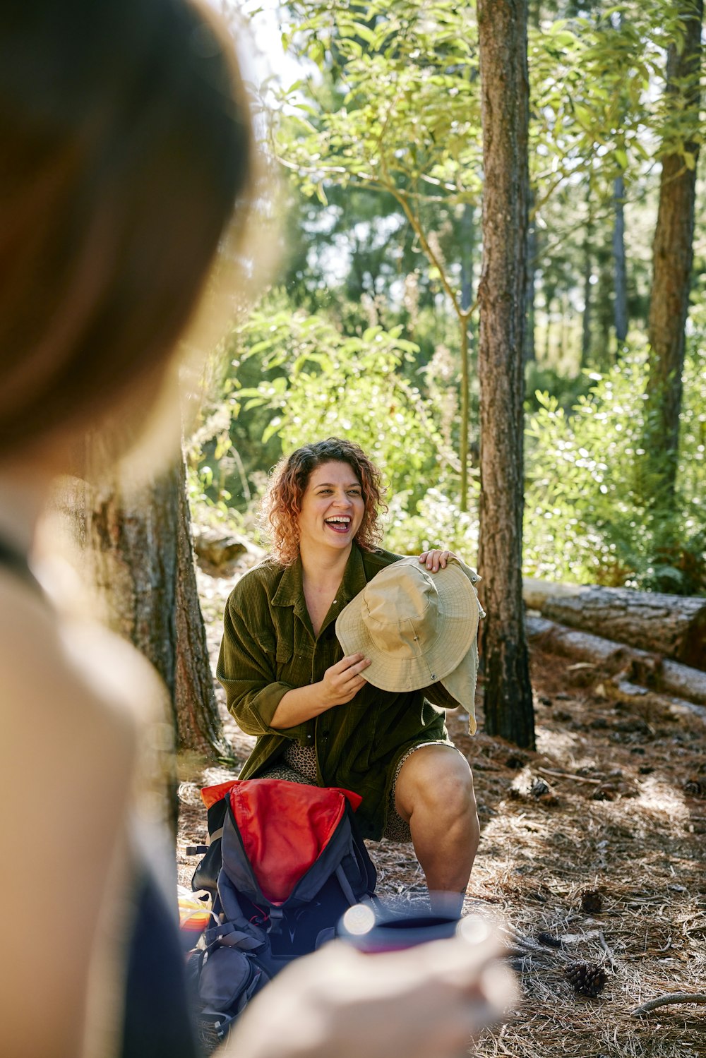 a woman sitting in the woods with a hat on