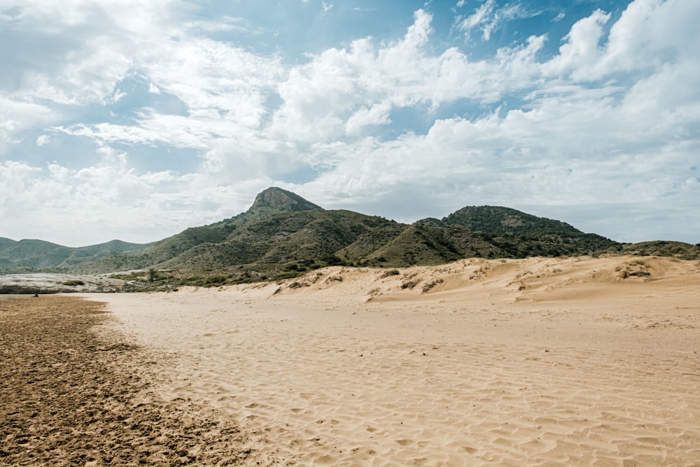 a sandy beach with mountains in the background