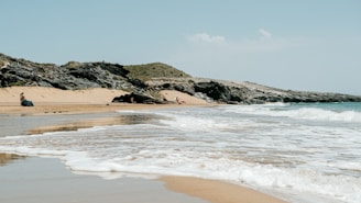 a person sitting on a beach next to the ocean