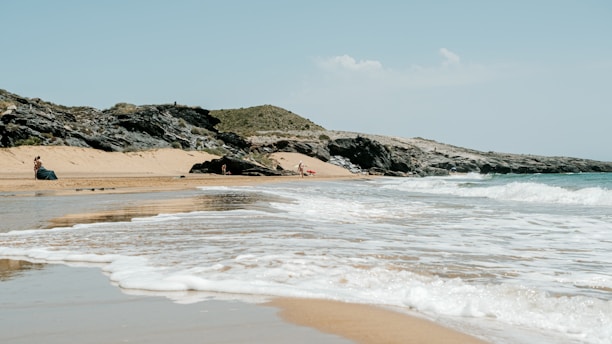 a person sitting on a beach next to the ocean