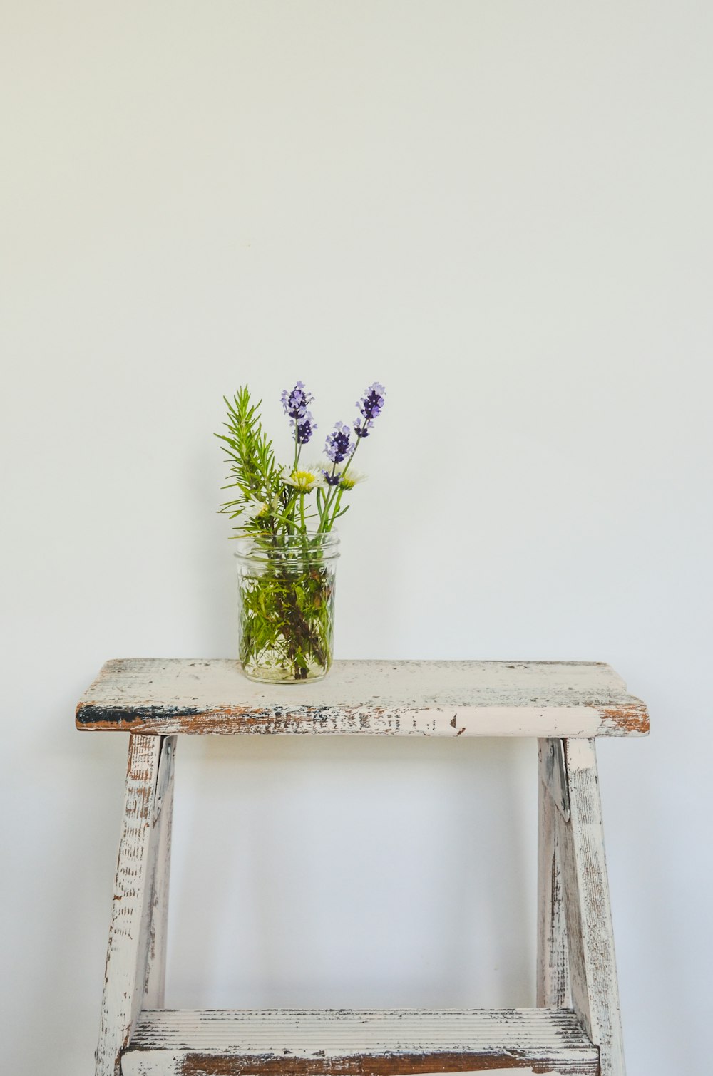 a wooden bench with a vase of flowers on top of it