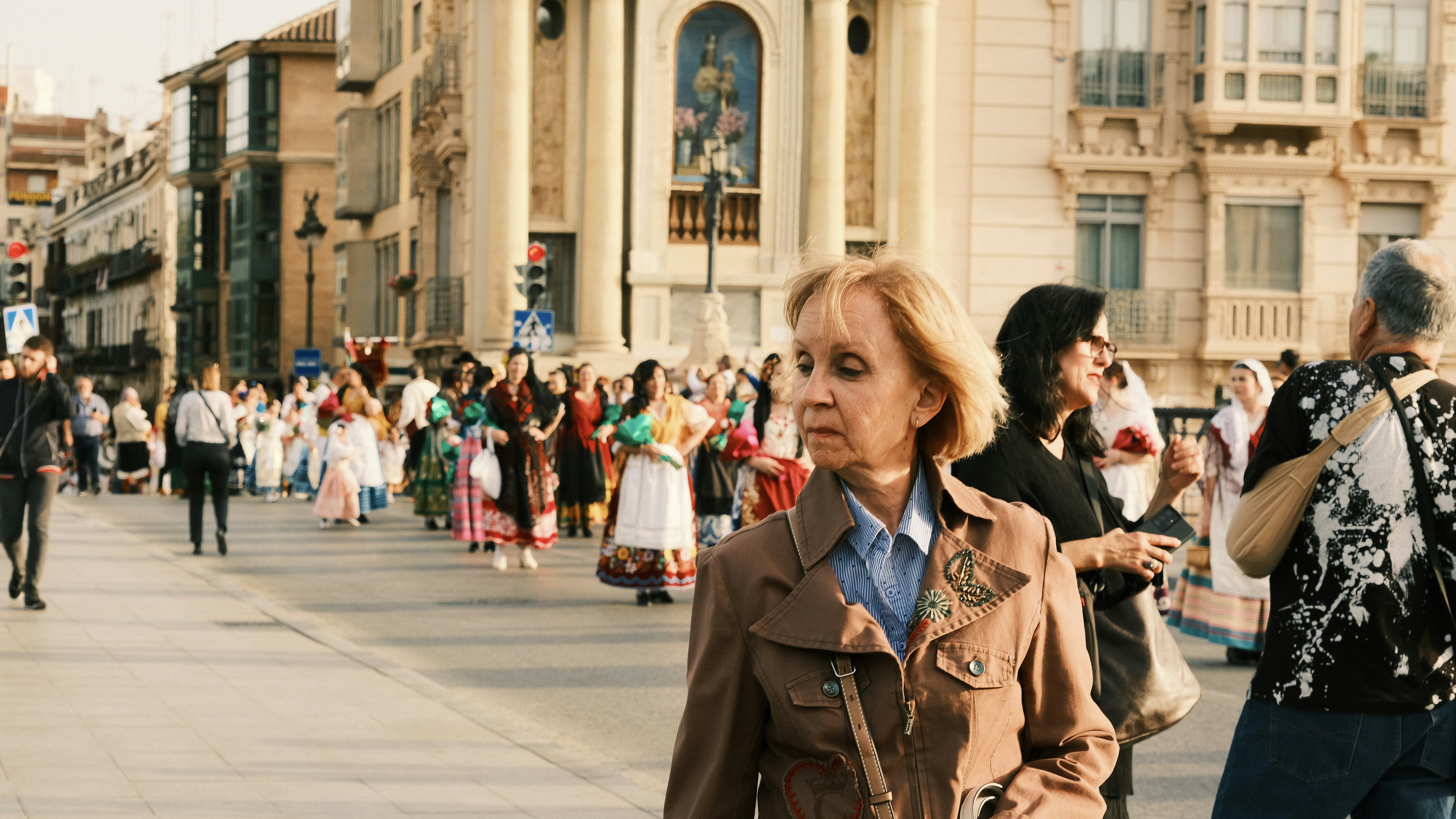 a group of people walking down a street next to tall buildings