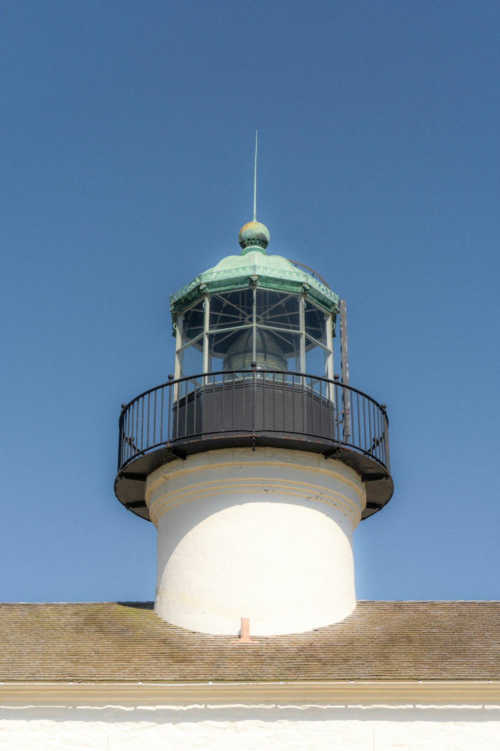 a white lighthouse with a green top on a clear day