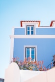 Exterior house wall painted bright blue with white trims on a sunny day