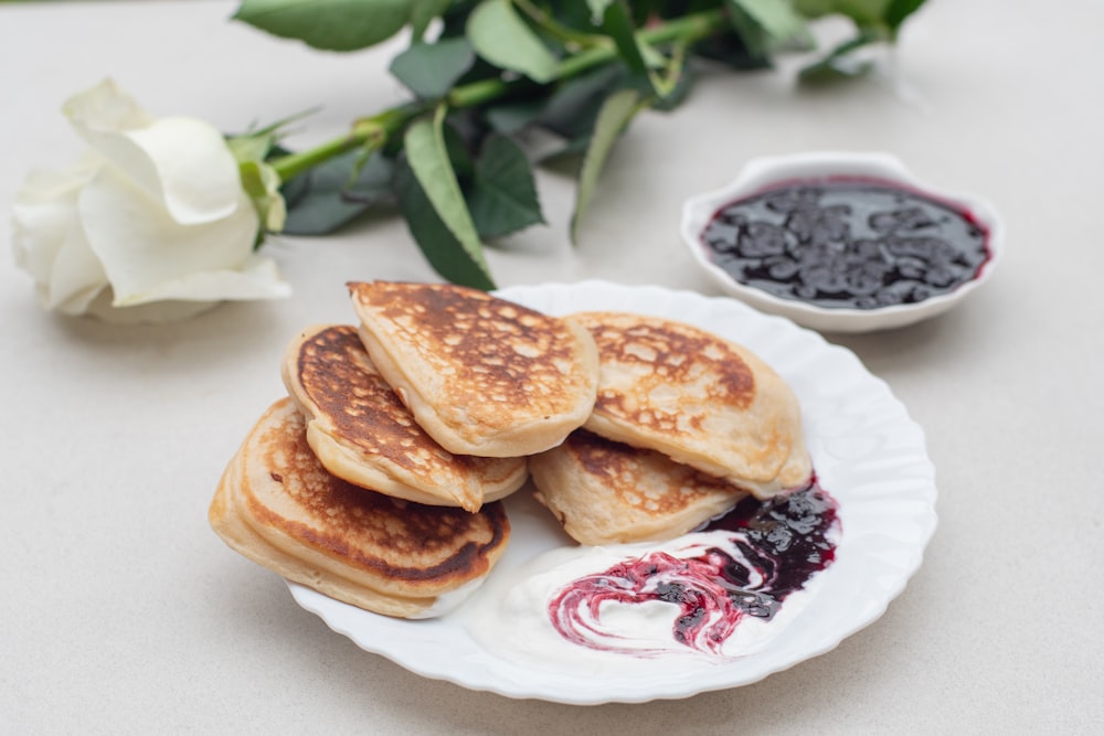 a white plate topped with pancakes next to a bowl of blueberries