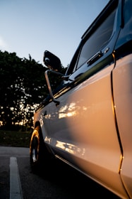 A close-up of a shiny truck grille reflecting vibrant colors at sunset on the highway.