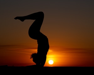 An influencer doing a creative yoga pose on a rooftop at sunrise.