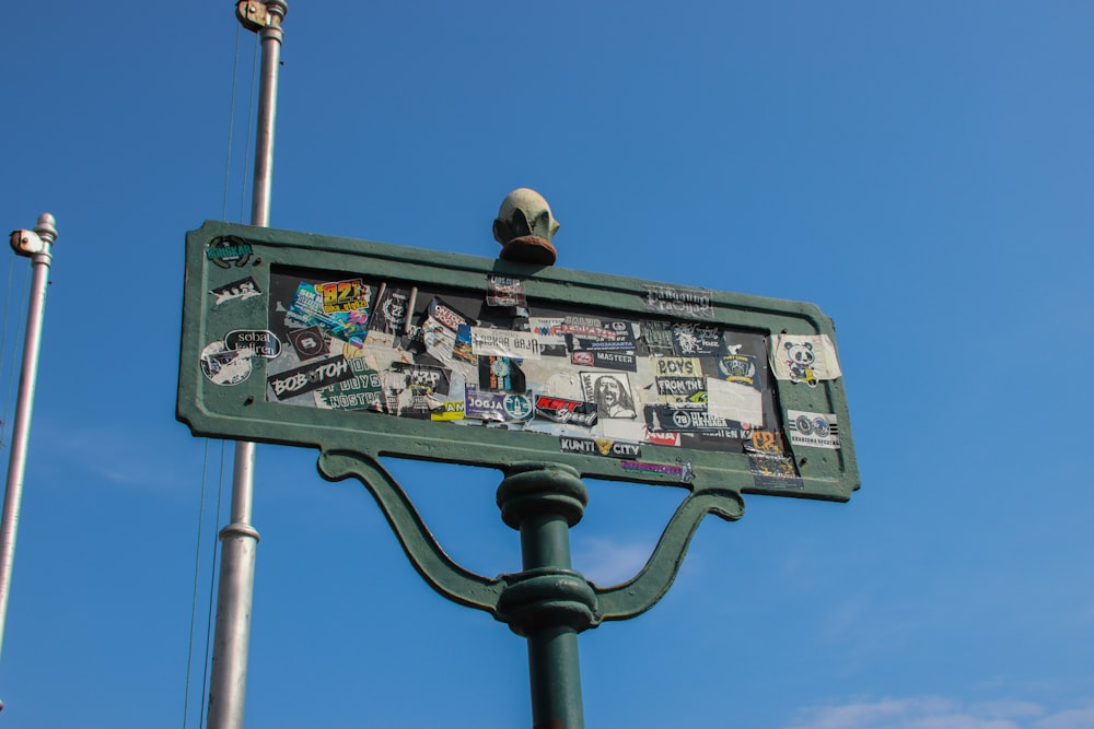 a green street sign with stickers on it