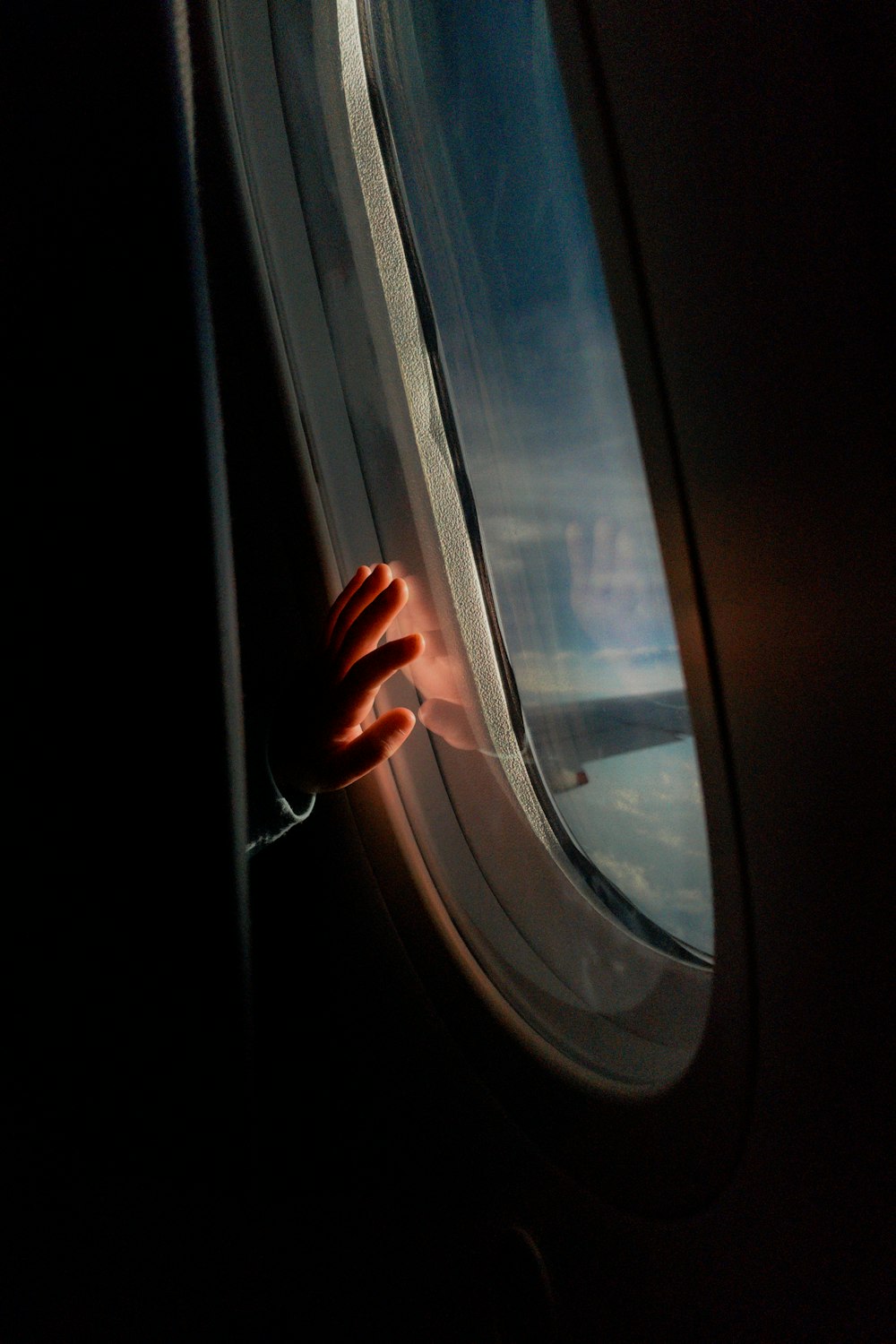 a person's hand on the window of an airplane