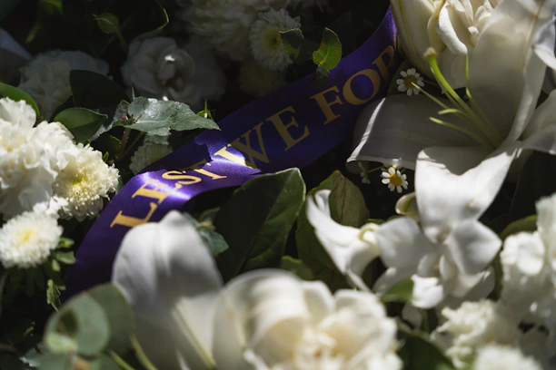 Warm light illuminating elegant floral arrangements in a serene and minimal memorial setting.