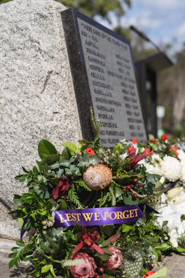 A wreath laid at a memorial site with subtle red flowers symbolizing resilience