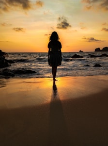 a woman standing on top of a beach next to the ocean