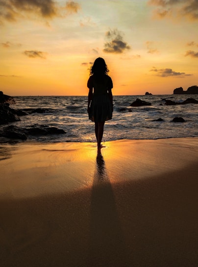 a woman standing on top of a beach next to the ocean