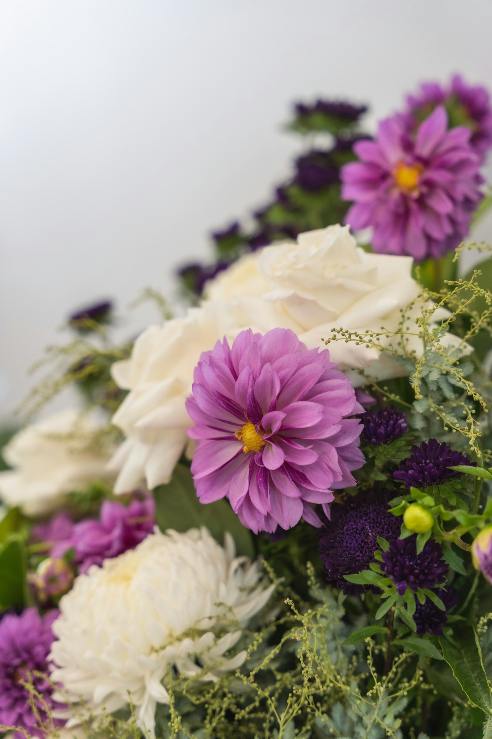 A close-up of a lush floral arrangement featuring burnt orange dahlias, sage green eucalyptus, and deep brown accents, artfully arranged in a rustic vase.