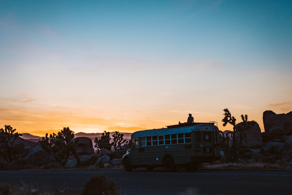 a bus driving down the road at sunset
