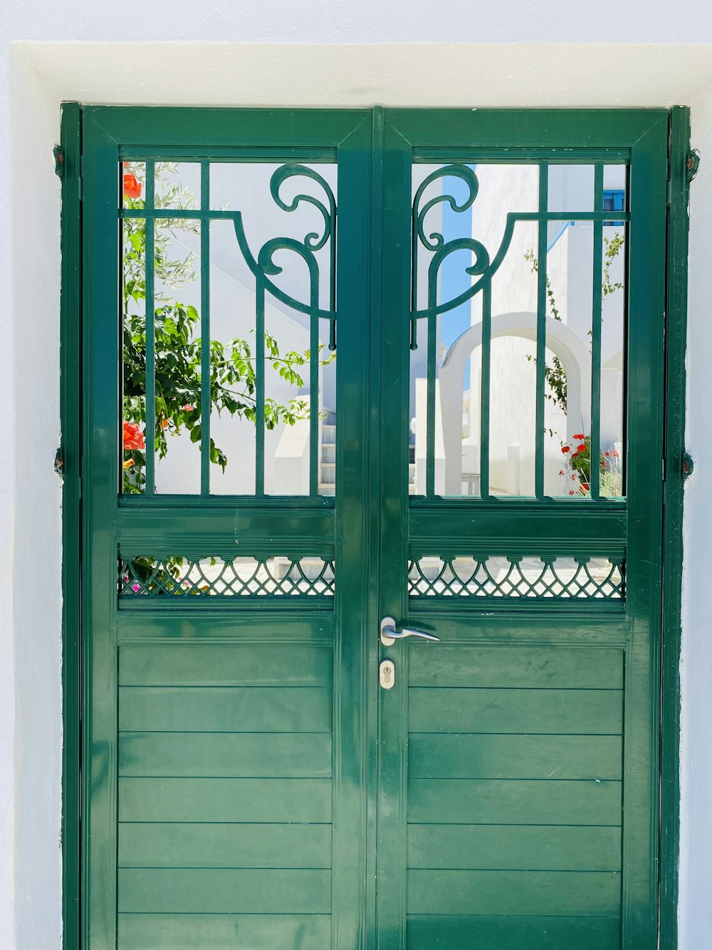 a pair of green doors with wrought iron