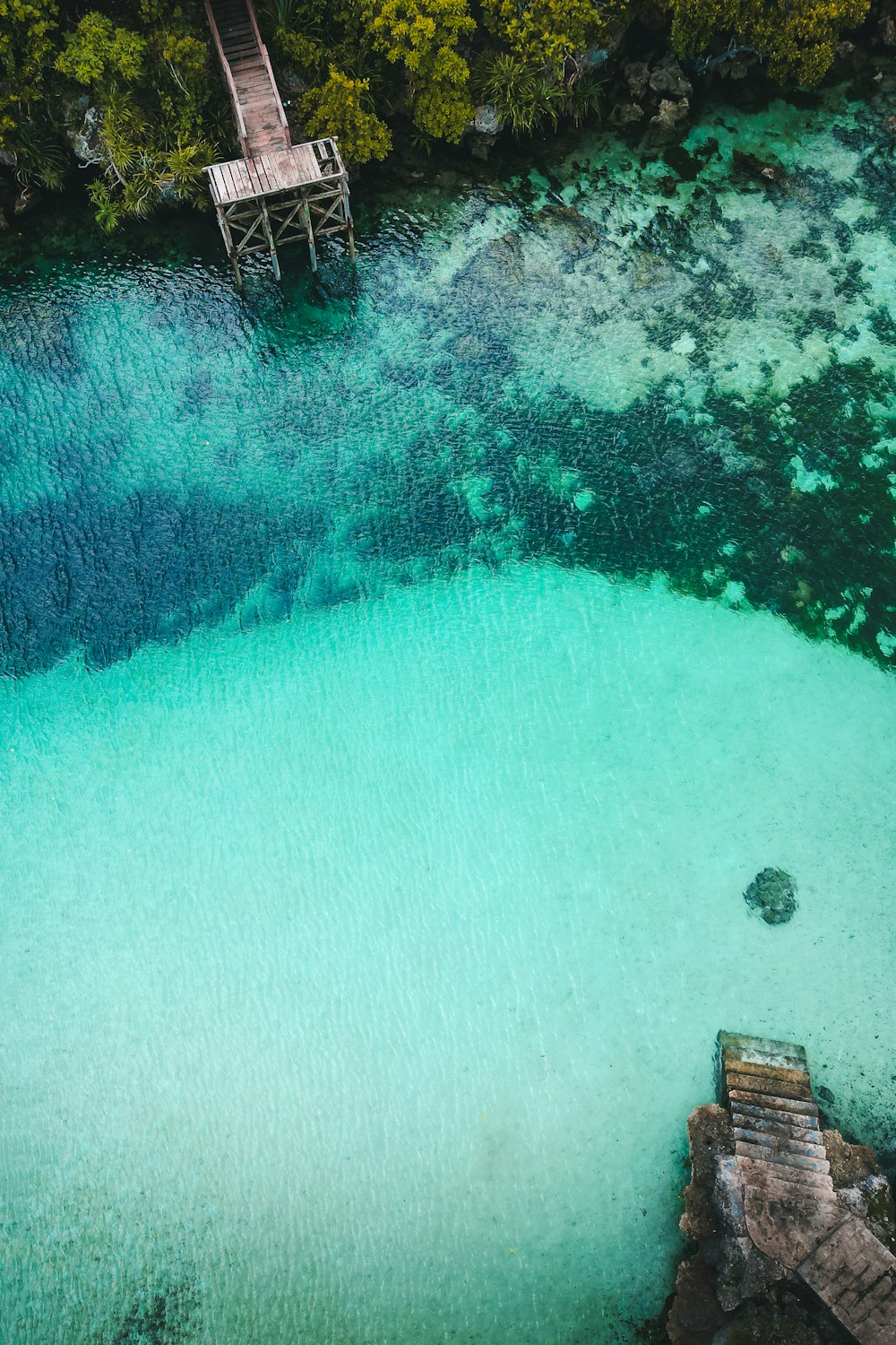 an aerial view of a body of water with a dock