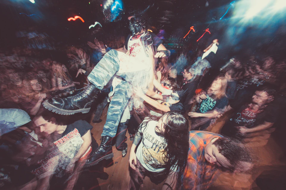 Crowded dance floor at a party with people dancing energetically under colorful lights