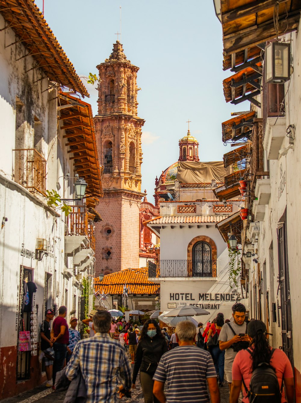 Un grupo de personas caminando por una calle junto a edificios altos