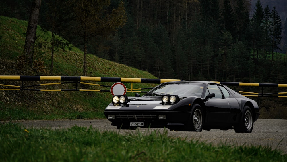 a black car driving down a road next to a forest