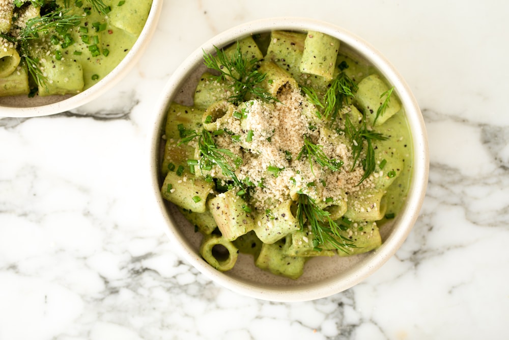two bowls of pasta with pesto and parmesan cheese