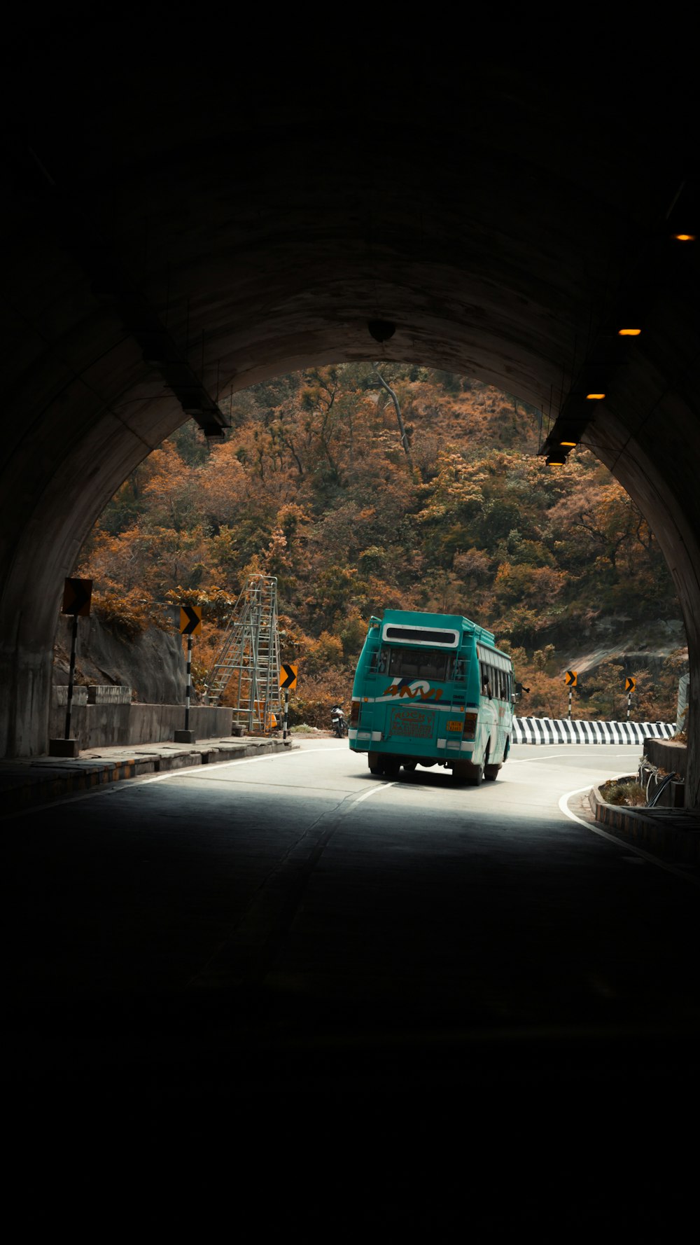 a green bus is driving through a tunnel