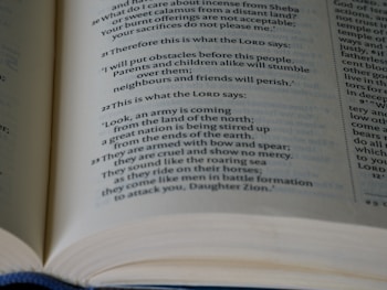 An open book displaying text with varying font styles and sizes, some in bold. The paper appears slightly yellowed, suggesting age or use. The text is printed in a clear serif font with visible indentation and formatting, likely a religious or literary text.