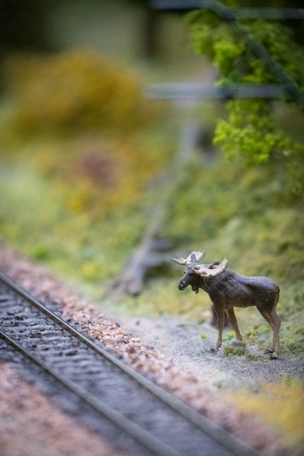a toy moose standing next to a train track