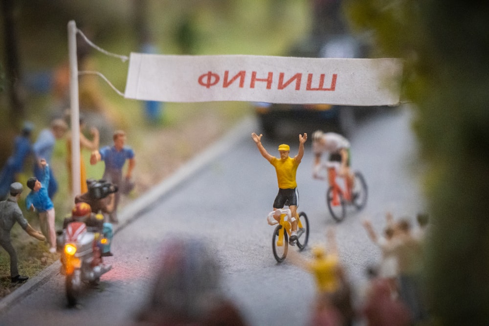 a group of miniature people riding bikes on a road