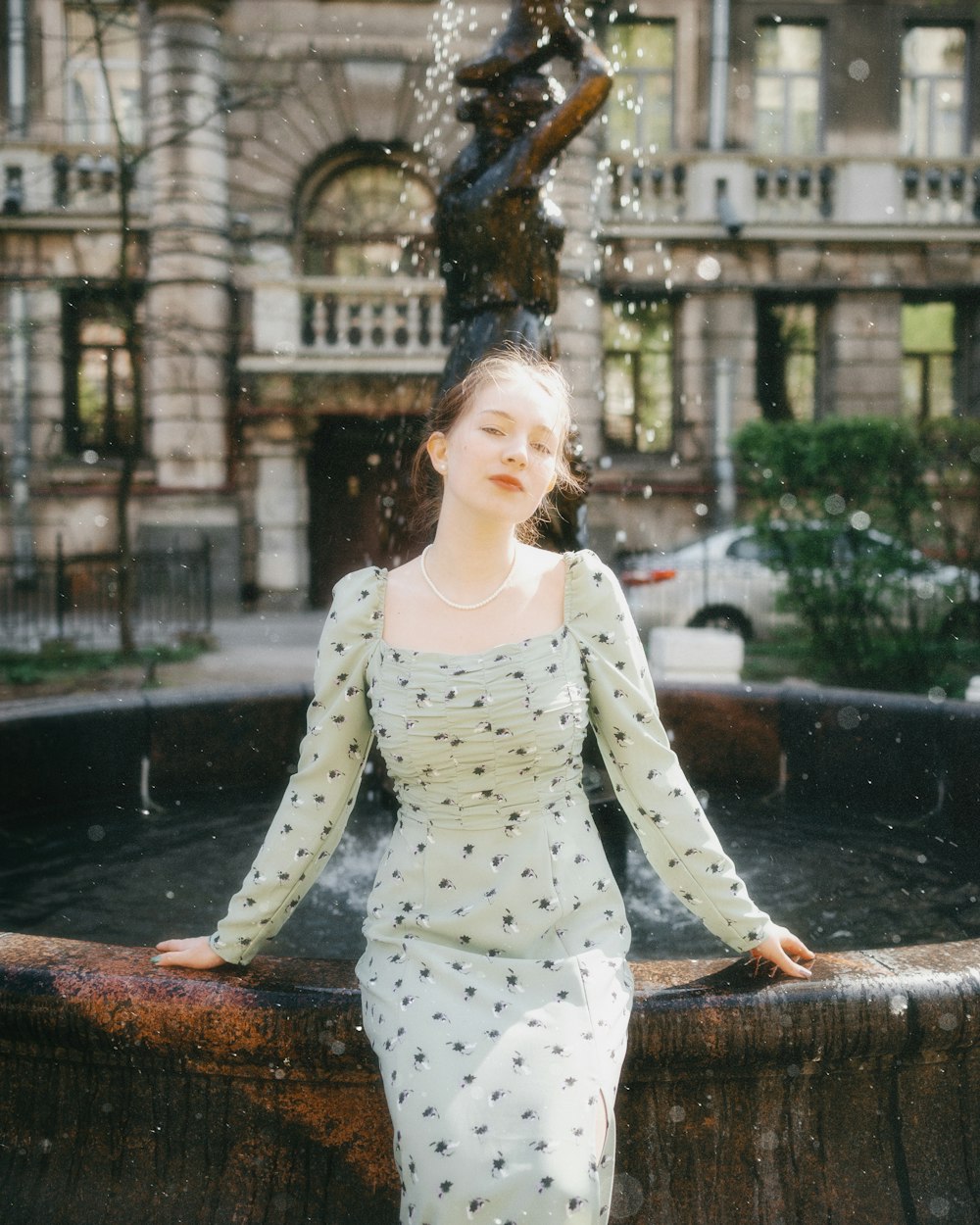 a woman in a dress standing in front of a fountain