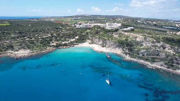 an aerial view of a beach with a boat in the water