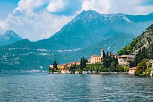 a scenic view of a town on a lake with mountains in the background