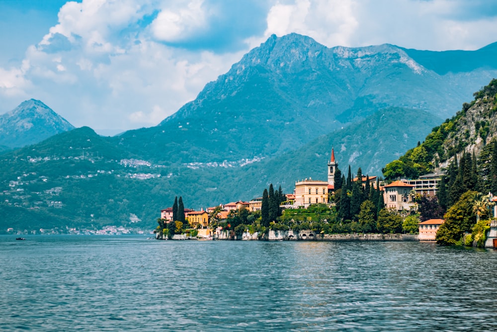 a scenic view of a town on a lake with mountains in the background