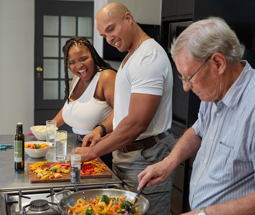 a group of people standing around a kitchen preparing food