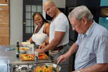 A lively group chopping fresh vegetables together in a sunlit kitchen.