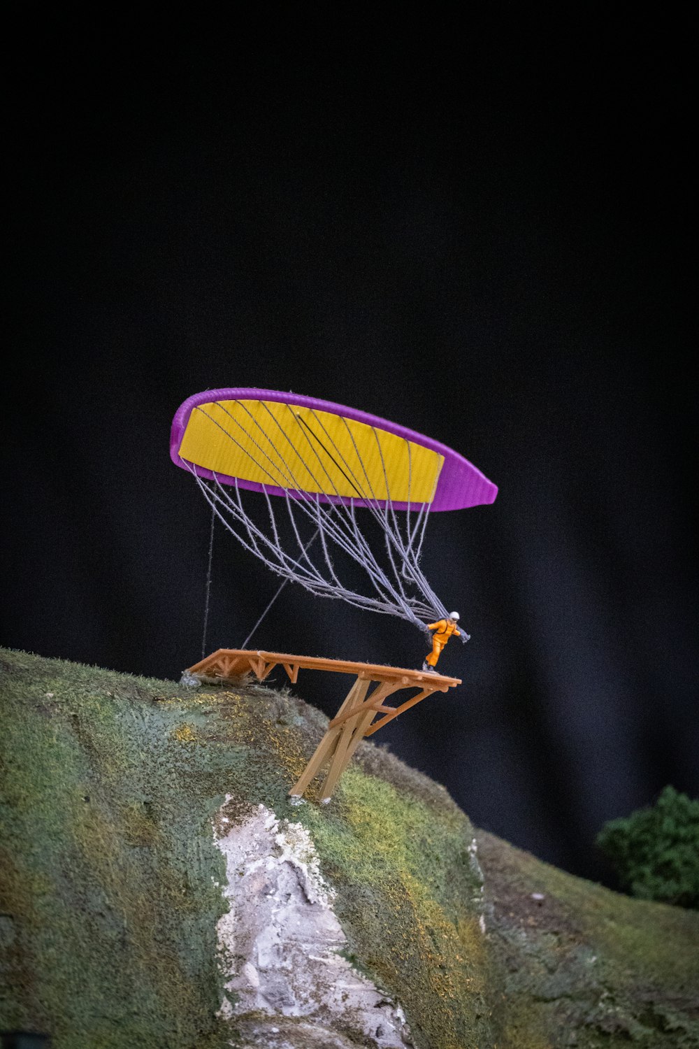 a yellow and purple kite sitting on top of a rock