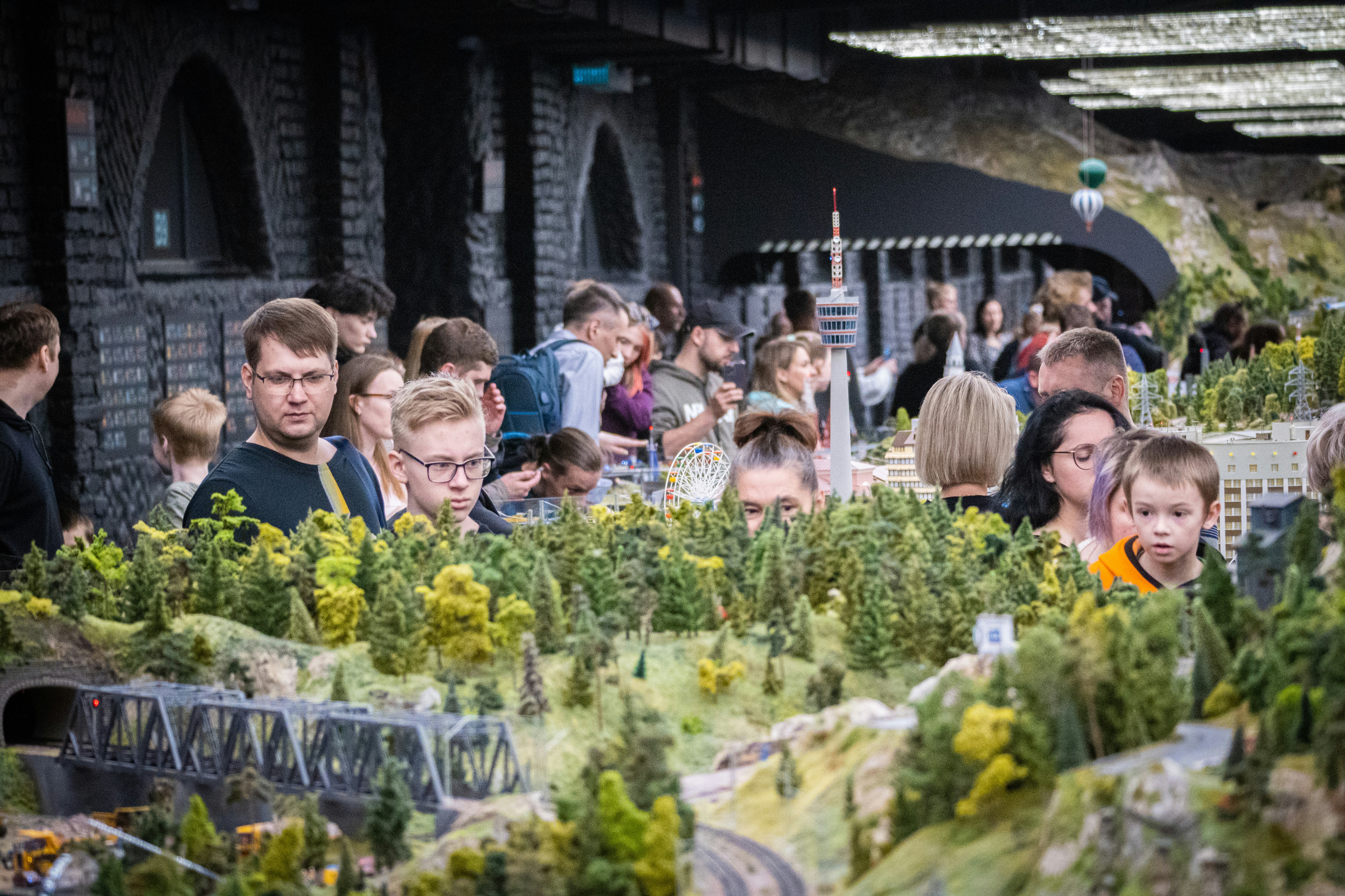 A crowd of people standing around a model train set photo – Free Saint ...