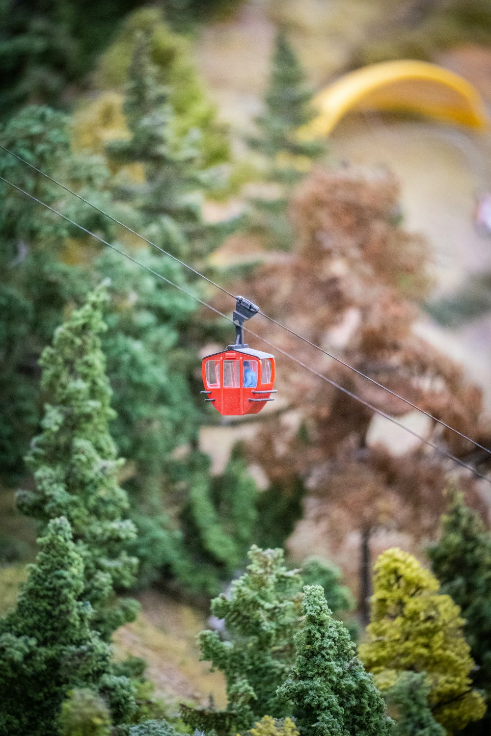 a red cable car traveling through a forest filled with trees