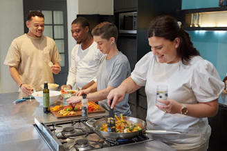 Young students happily cooking together in a bright, modern kitchen classroom