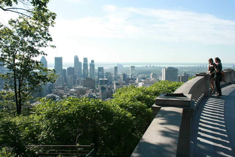 two people sitting on a bench overlooking a city