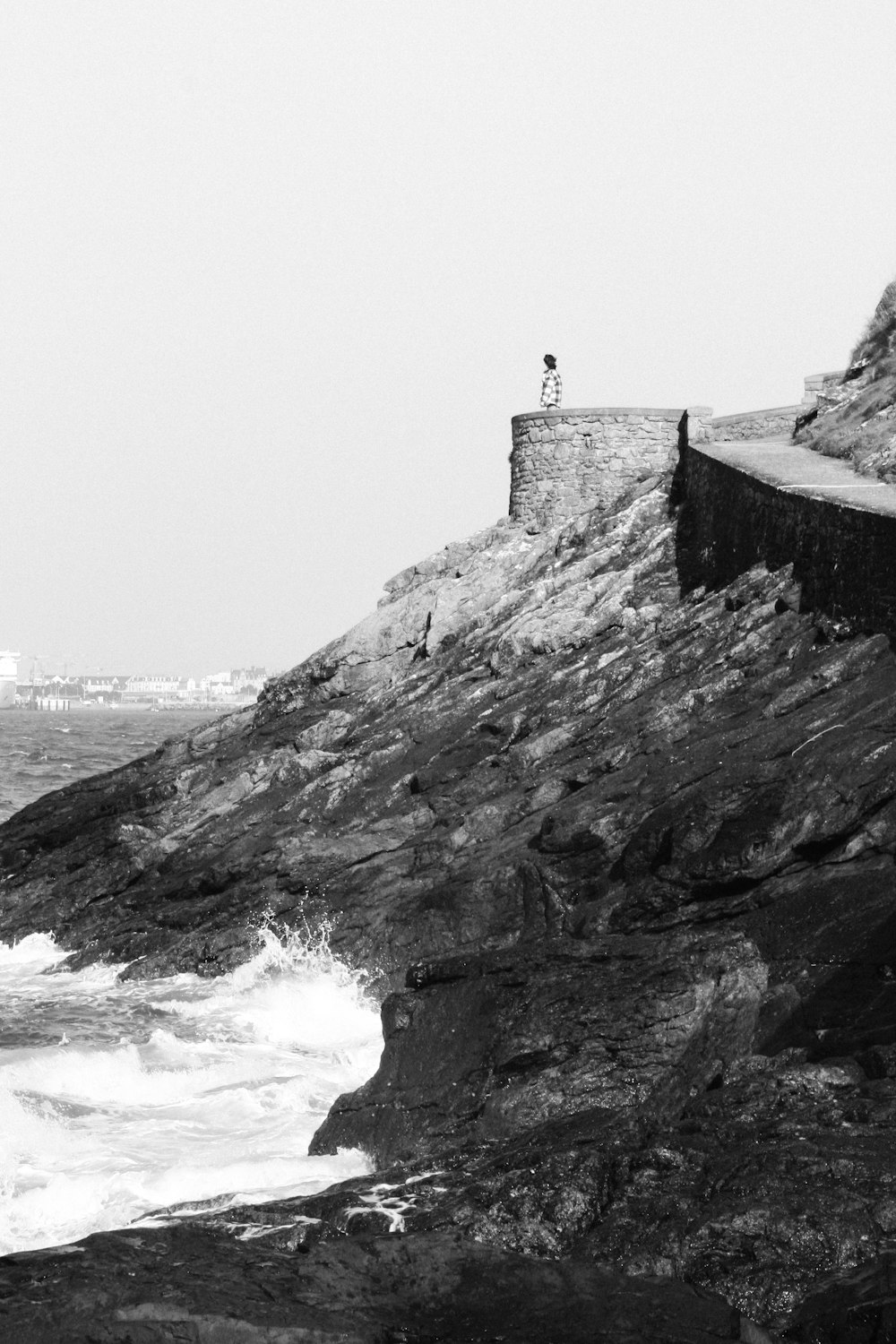 Una foto in bianco e nero di una persona in piedi su una scogliera