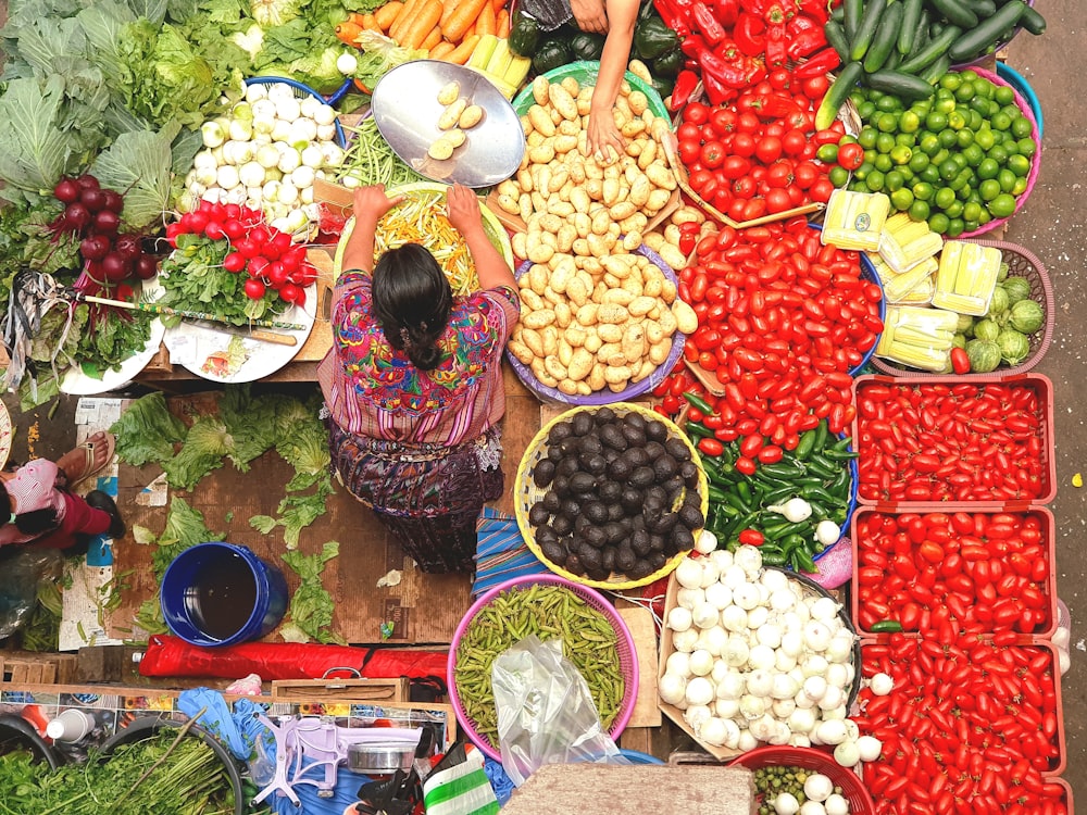 Una mujer parada frente a una mesa llena de muchas verduras