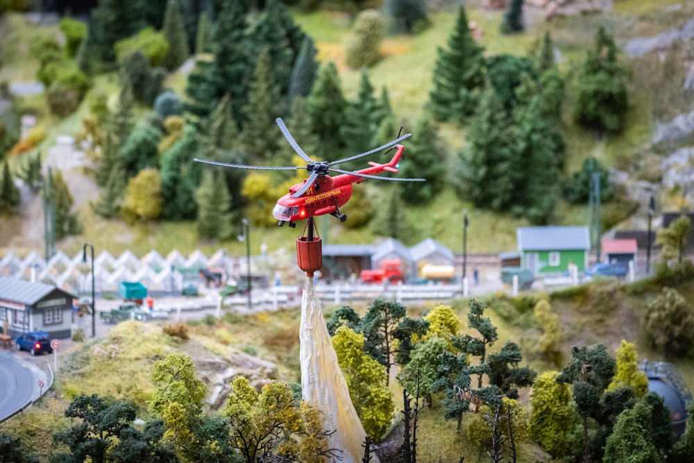 a red helicopter is flying over a town