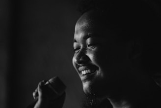 A close-up portrait of a smiling artist holding a microphone.