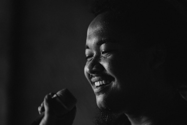 Close-up of a musician holding a microphone, smiling warmly during a recording session.