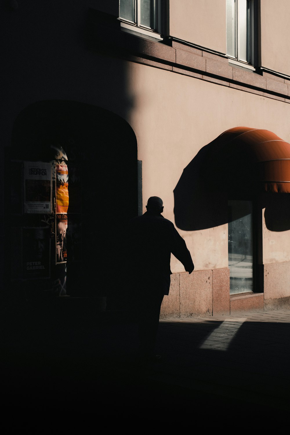 a man walking down a street next to a tall building