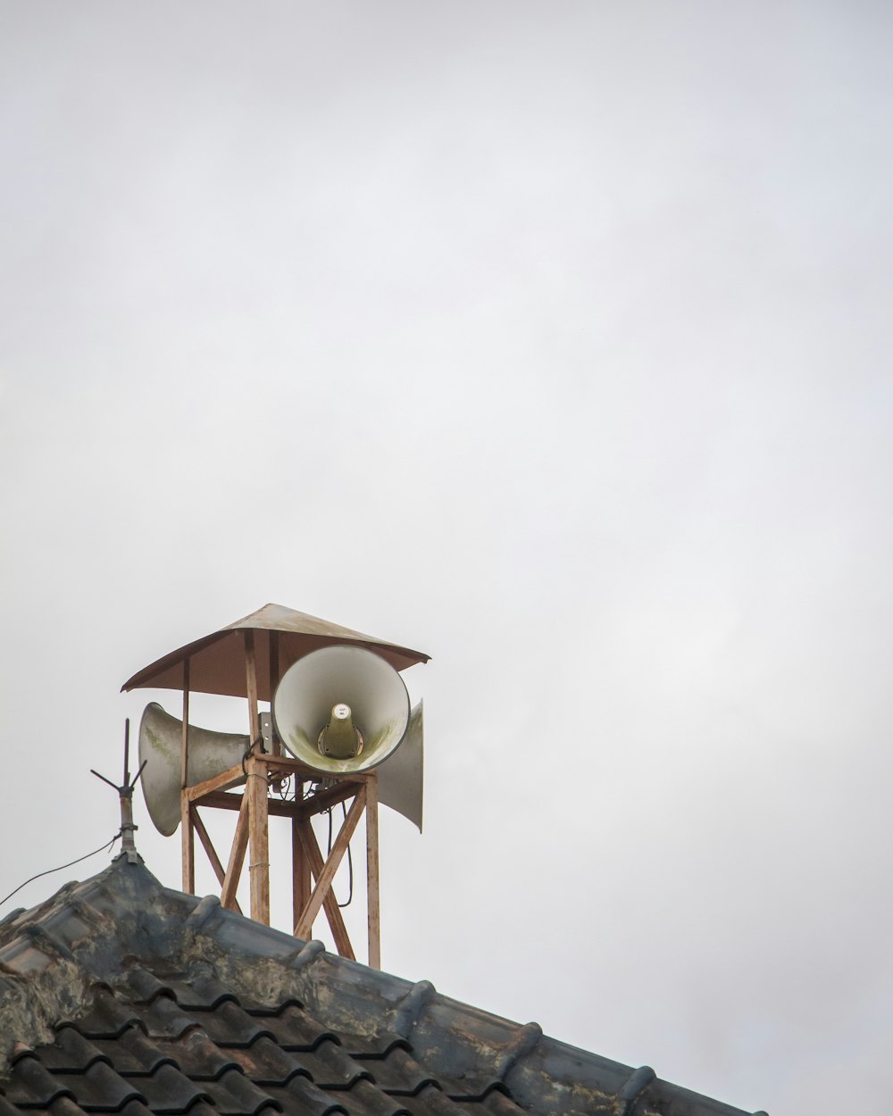 a bell on top of a roof with a sky background