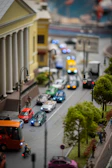An intricate urban street scene crafted from blocks, complete with tiny vehicles and street lamps.