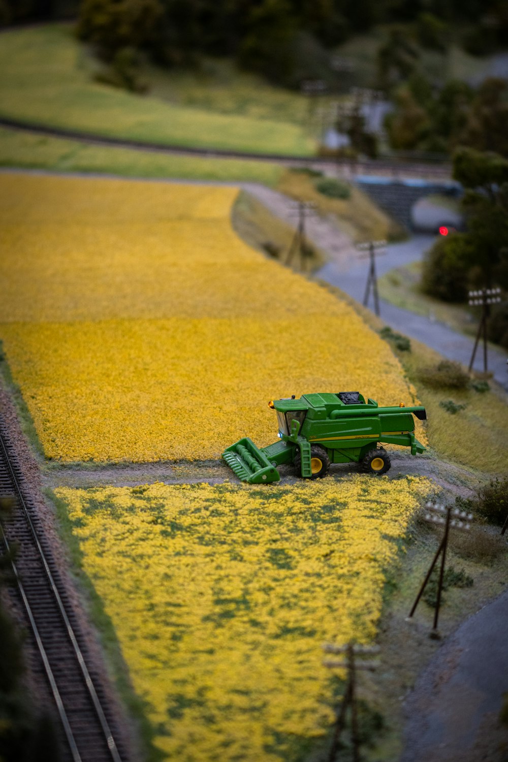 a green truck driving down a road next to a field of yellow flowers